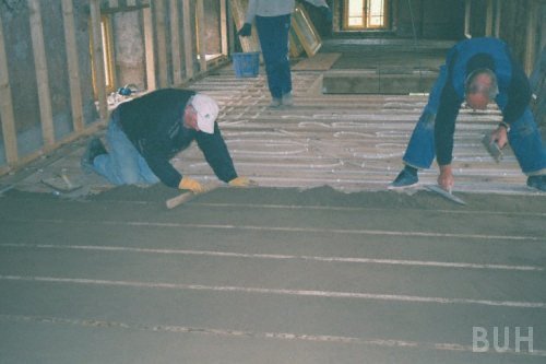 photo of workers infilling around u f h pipes in suspended timber floor